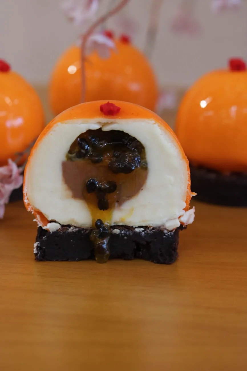 Entremet laranja cortado ao meio mostrando recheio cremoso e maracujá